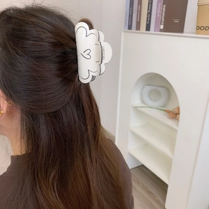 Détail d'une pince à cheveux blanche à motif cœur portée par un mannequin