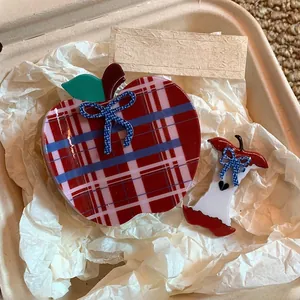 Detail of red checkered apple-shaped hair claw clips with blue polka dot bows in a gift box