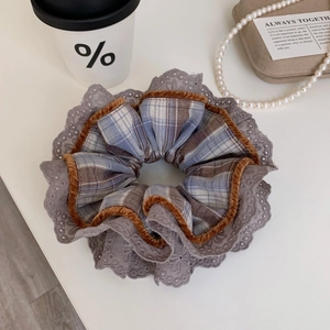 Plaid scrunchie with lace edge and velvet trim shown in a cozy lifestyle setting