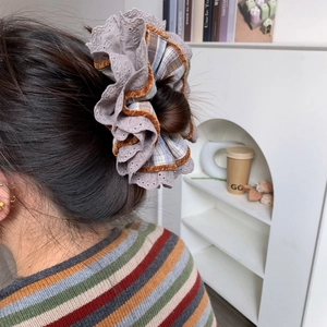 Detail of multi-layered plaid scrunchie with lace and velvet edges worn on hair