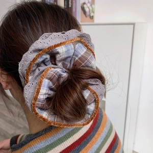 Detailed shot of large checkered hair scrunchie with lace overlay and orange velvet trim