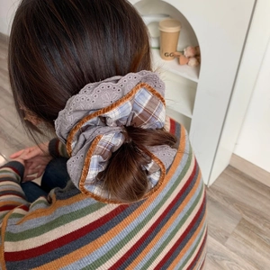Detail of layered plaid scrunchie with orange velvet trim on a person's hair