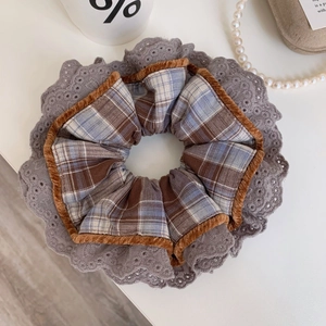 Close-up of retro plaid scrunchie with brown corduroy edges and grey lace embroidery