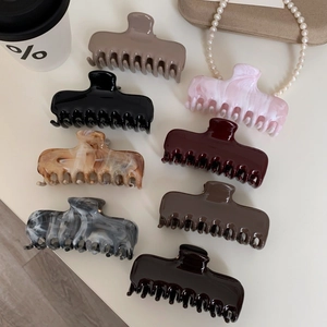 Detail view of 8 large acetate hair claws in diverse marble patterns and solid colors