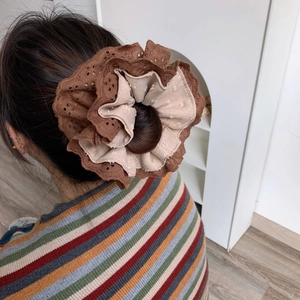 Detail of multi-layered lace scrunchie with brown and beige texture and ruffled edges
