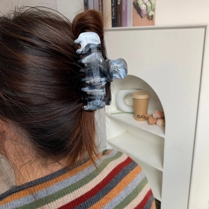 Detailed macro shot of large marble-patterned acetate hair claw clip on model hair