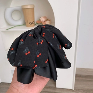 Gros plan du nœud papillon noir avec motif cerise rouge et texture en mousseline multicouche