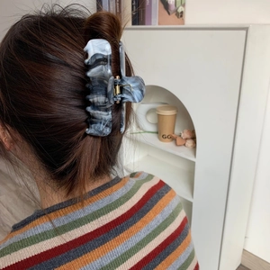 Detail showing marble texture acetate hair claw clip worn on long hair for a half-up style
