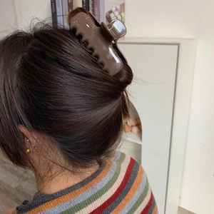 Detailed close-up of a large brown glossy acetate claw clip styling thick hair perfectly