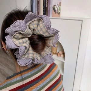 Close-up of four-layer purple lace and green plaid hair scrunchie shown in use
