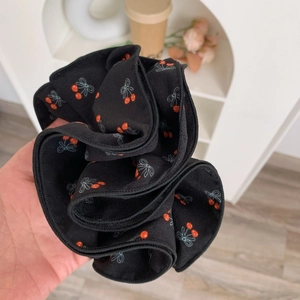 Vue détaillée d'un chouchou noir à motifs de cerises et texture plissée fine