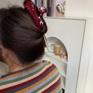 Detail view of a large burgundy acetate hair claw clip worn in a stylish bun hairstyle