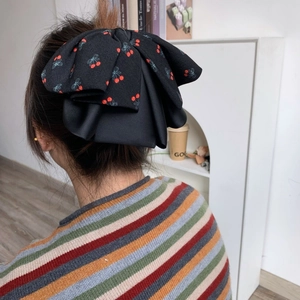 Grand chouchou noir avec motif de cerises porté sur les cheveux d'une femme
