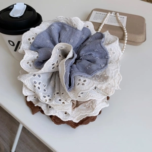 Close-up of layered lace scrunchies in grey and beige with soft fabric texture