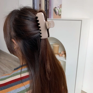 Close-up of a large apricot matte shark hair clip worn in a stylish back-view hairstyle
