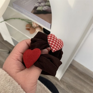 Close-up of a brown hair scrunchie with plush red heart and plaid heart accents