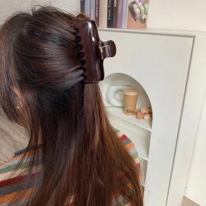 Detail view of large dark brown acetate hair claw clip on a half-up hairstyle