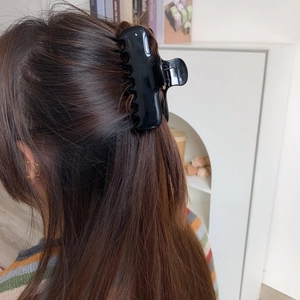 Classic glossy black oversized claw clip securing a full updo hairstyle on long hair