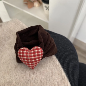 Close-up of heart-shaped plaid fabric ornament on a brown knit hair accessory