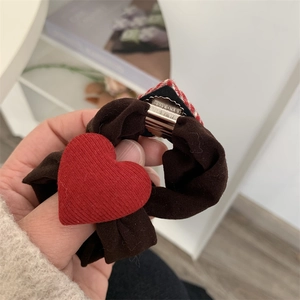 Detail of handmade brown fabric hair clip featuring a red textured heart and metal clip