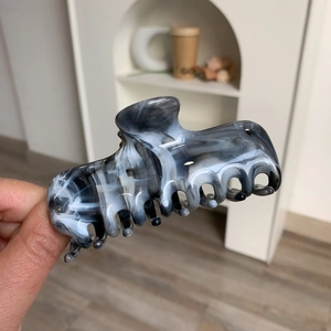 Detailed close-up of marble pattern acetic acid hair claw clip held in hand