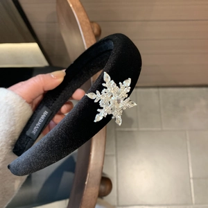 Detail of handmade black velvet headband featuring a large sparkling silver snowflake rhinestone