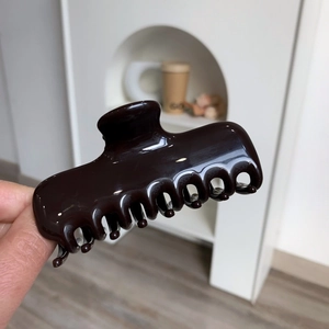 Detail of glossy dark coffee acetate hair claw clip with a creative bear apron design
