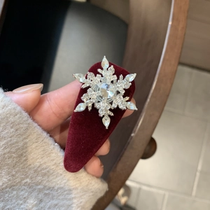 Close-up of a silver snowflake hairpin with sparkling rhinestones on red velvet fabric