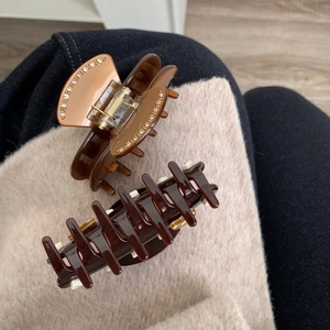 Dettaglio di eleganti mollette in acetato con strass e denti classici in resina caffè scuro