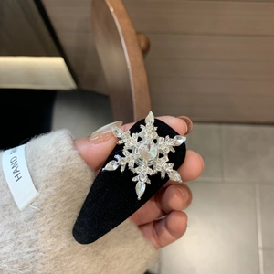 Detail showing a rotating crystal snowflake hair clip with black velvet headband base