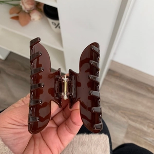 Dettaglio della molletta per capelli in acetato marrone scuro lucido con molla dorata