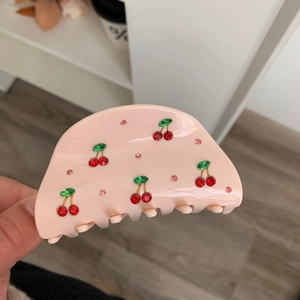 Détail d'une pince à cheveux rose avec cerises décorées de strass rouges et verts