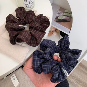 Detail of blue and brown plaid scrunchies with white handmade labels in a cozy setting