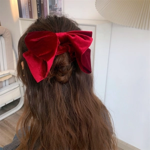 Gros chouchou en velours rouge avec nœud élégant porté sur des cheveux ondulés