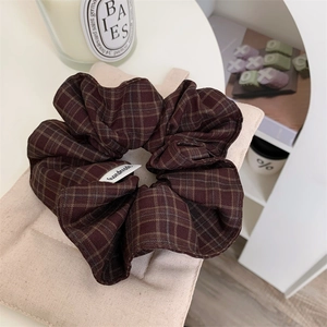 Minimalist dark coffee plaid scrunchie with handmade label on a clean desk