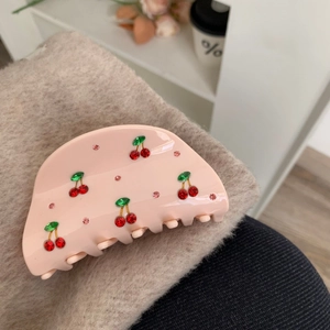 Pince à cheveux cerise rose en acétate avec strass sur un fond beige doux et élégant
