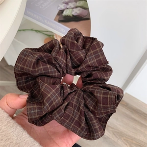 Detailed view of deep brown plaid fabric scrunchie with soft pleated texture and retro style