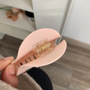 Détail de la pince à cheveux en acétate rose montrant le ressort et la texture lisse