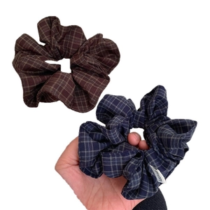 Two-pack checkered fabric scrunchies in brown and navy blue with handmade label