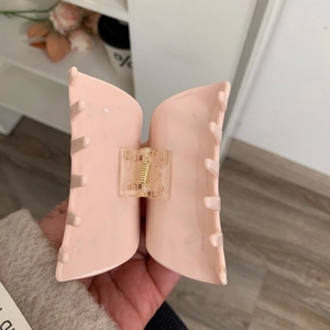 Détail de la pince à cheveux en acétate rose avec ressort en métal doré et fini poli