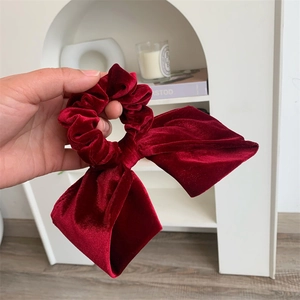 Gros plan sur la texture d'un grand chouchou nœud en velours rouge de luxe élégant