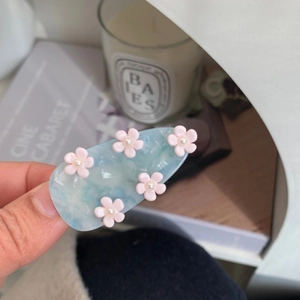 Detailed view of blue marble hair clip with pink 3D flowers and white pearls