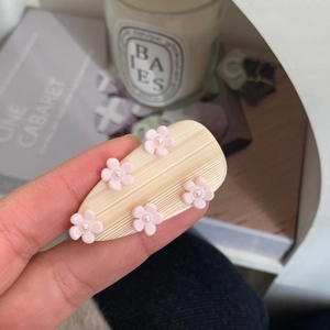 Detailed shot of a beige water drop hair clip with 5 pink flowers and pearl centers