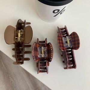 Detail view of brown acetate claw clips with plaid patterns and sparkling rhinestones