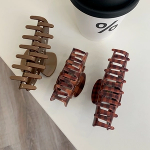 Detailed view of checkered and solid brown claw clips on a white minimalist surface