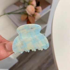Detailaufnahme einer hellblauen Haarklammer mit Karomuster und transluzentem Finish