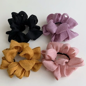 Détail de quatre chouchous en tissu coloré montrant la texture tissée et l'élastique