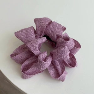 Gros plan d'un chouchou en tissu violet montrant le tissage grossier et le noyau élastique