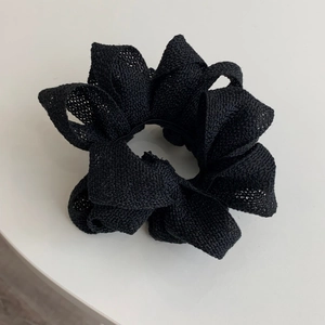 Gros plan sur chouchou noir oversize en tissu texturé avec design plissé à volants