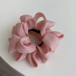 Gros plan détaillé d'un chouchou en tissu rose montrant le tissage et les plis